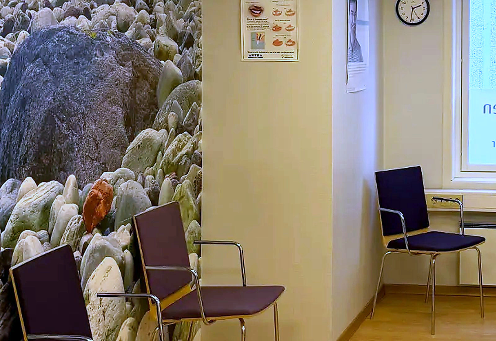 Venterommet sett mot vinduet, med steinstrandmuralen og stoler i dagslys